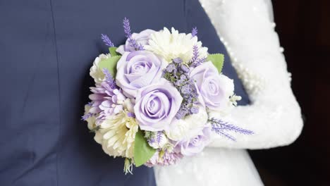 Slow-motion-shot-of-the-brides-bouquet-of-flowers-at-the-back-of-the-groom