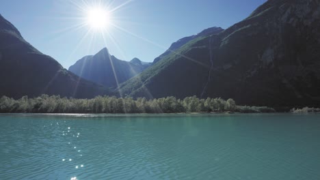 Beautiful-lake-scene-with-sunlight-reflecting-on-the-water,-surrounded-by-green-mountains