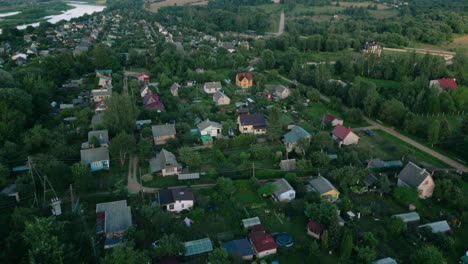 Aerial-footage-of-a-serene-Latvian-village-showcasing-quaint-houses-with-gardens-and-a-nearby-river