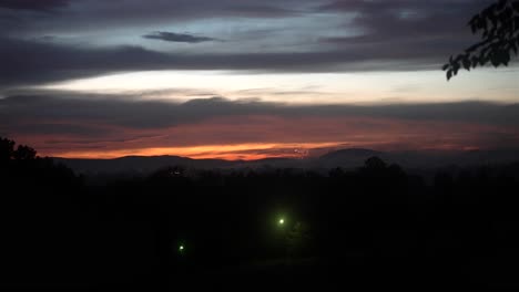 Panoramic-view-of-fireworks-bursting-off-in-distance-in-front-of-beautiful-dusk-glow-in-sky