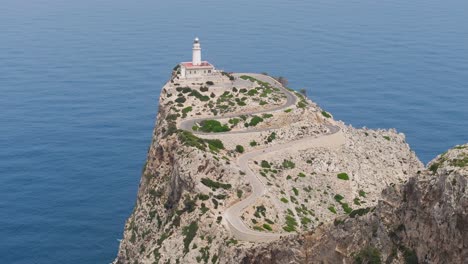 Aerial-view-of-blue-turquoise-water-and-lighthouse-on-cliff-edge,-Mallorca