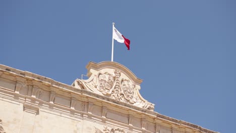 Auberge-De-Castille-Außen-Mit-Maltesischer-Flagge-Und-Geschnitzten-Wappen-Vor-Blauem-Himmel