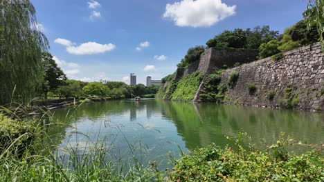 Friedlicher-Blick-Auf-Einen-Wasserweg-Mit-Alten-Steinmauern-Und-üppigem-Grün-In-Japan