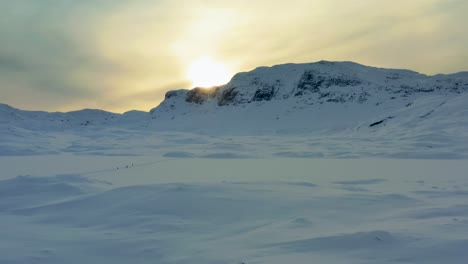 Aerial-pullback-over-barren-snow-covered-Haukelifjell-mountain-pass-in-Vinje-Telemark-Norway-at-sunset-with-outpost-homes