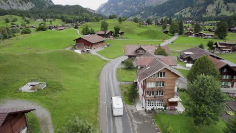 Camper-driving-through-a-picturesque-Swiss-village-with-lush-green-landscapes