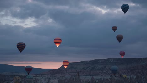 Heißluftballons-Füllen-Den-Wolkigen-Grauen-Himmel-Im-Morgengrauen-Vor-Kappadokien,-Türkei