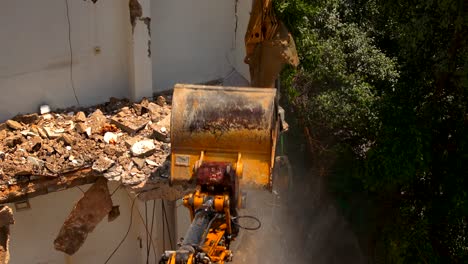 Excavator-arm-demolishing-an-old-building,-Aerial-view