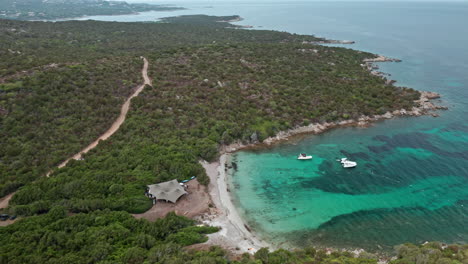 A-secluded-beach-in-sardinia-with-turquoise-water-and-lush-greenery,-aerial-view