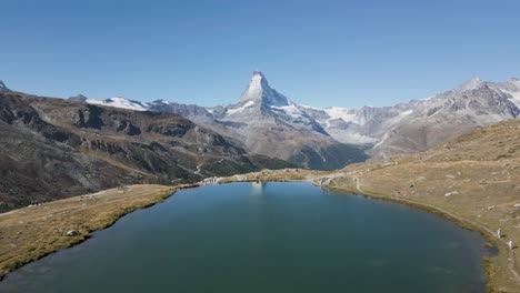 Lake-view-with-clear-blue-water-surrounded-by-mountains,-showcasing-the-Matterhorn-in-the-distance