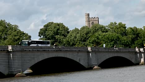 SPRINTERS-Travel-Coach-over-Putney-Bridge-in-front-of-All-Saints,-Fulham,-London,-United-Kingdom