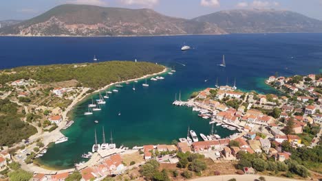 Aerial-drone-view-of-Fiskardo,-Kefalonia-Greece-with-cruise-ship-anchored-in-the-bay