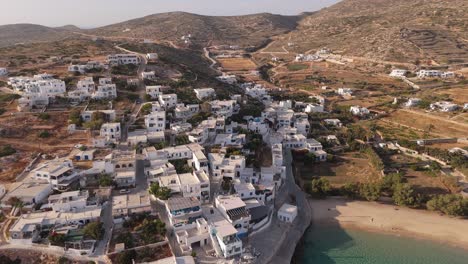 Casas-De-Bloques-Blancos-Sobre-Playas-Tranquilas-Y-Aguas-Cristalinas-De-Donousa,-Grecia,-Mientras-Las-Carreteras-Serpentean-Entre-Las-Colinas