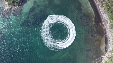 Boat-creating-a-perfect-circle-in-turquoise-waters-of-Sardinia,-aerial-view