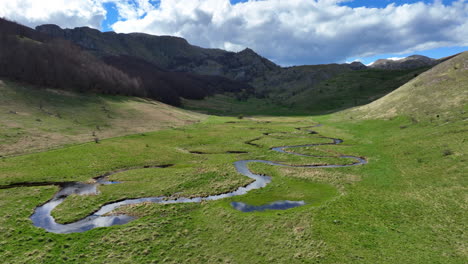 Flight-over-a-winding-mountain-stream-with-clear-water-on-a-sunny-spring-day