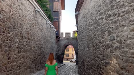 A-young-red-haired-woman-in-a-green-dress-is-walking-along-Hisar-Kapia-when-someone-calls-out-to-her-and-she-turns-around