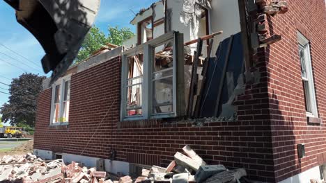 Excavator-demolishing-wall-and-window-of-house-during-sunny-day-in-USA