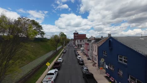 Colorful-row-of-houses,-walking-pedestrian-on-sidewalk-and-parked-cars-in-american-town