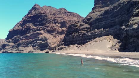 Idyllic-scene-of-a-woman-relaxing-unwinding-at-unspoiled-virgin-beach-in-Gran-Canaria,-Spain-during-summer-time-on-vacations