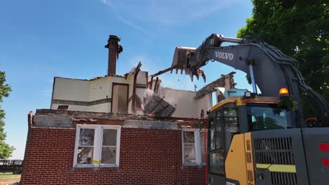 Close-up-of-excavator-demolishing-rusty-old-single-family