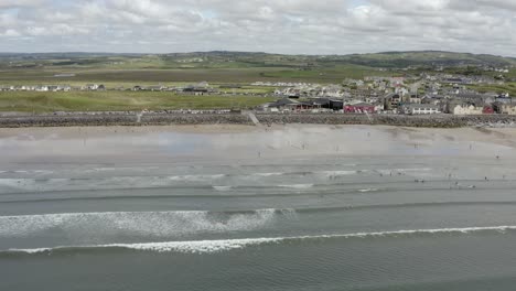 Aerial-dolly-along-expansive-sandy-surfing-beach-at-Lahinch,-Ireland