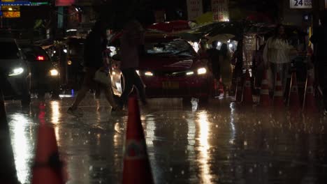 Rainy-night-in-Bangkok-Chinatown,-bustling-street-scene-with-cars,-scooters,-and-pedestrians