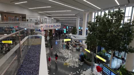 Vista-Elevada-De-Pasajeros-En-La-Remodelada-Terminal-B-De-LGA,-Con-Pasajeros-Caminando-Hacia-Las-Puertas-Y-Visitando-Tiendas.