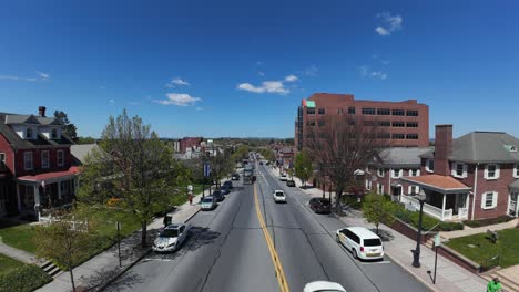 Statische-Drohnenaufnahme-Von-Lastwagen-Und-Autos-Auf-Der-Hauptstraße-Einer-Amerikanischen-Stadt-Im-Sommer