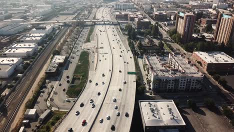 Toma-Aérea-De-Una-Transitada-Autopista-En-Los-Ángeles-Con-El-Hotel-Burbank-Al-Atardecer