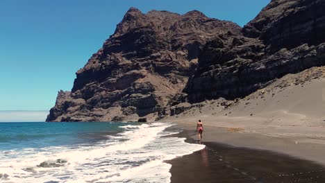 Idyllic-scene-of-a-woman-relaxing-unwinding-at-unspoiled-virgin-beach-in-Gran-Canaria,-Spain-during-summer-time-on-vacations