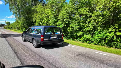 Aufnahme-Eines-Alten-Volvo-Geländewagens,-Der-An-Einem-Sonnigen-Tag-Durch-Eine-Landstraße-Fährt