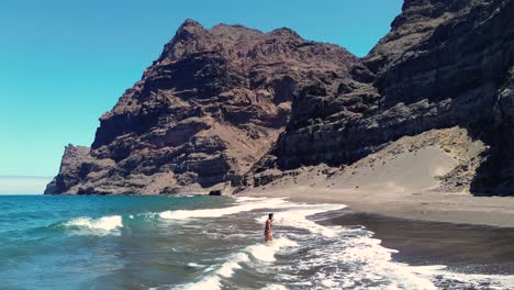 Idyllic-scene-of-a-woman-relaxing-unwinding-at-unspoiled-virgin-beach-in-Gran-Canaria,-Spain-during-summer-time-on-vacations