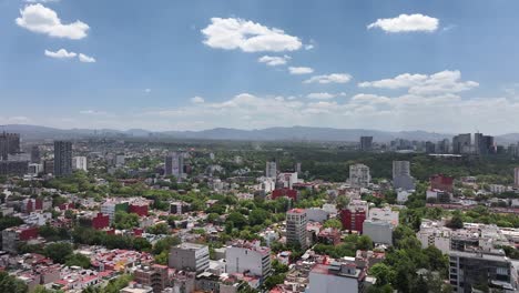 Dolly-in-drone-aerial-over-Condesa-neighborhood,-revealing-Aztlan-Park's-famous-Fortune-Wheel