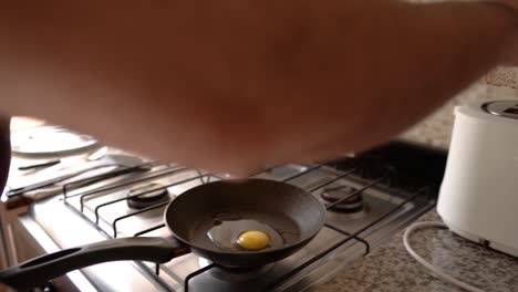 Una-Toma-Detallada-De-Un-Hombre-Preparando-Pan-Tostado-Y-Huevo-En-La-Sartén-Para-El-Desayuno.