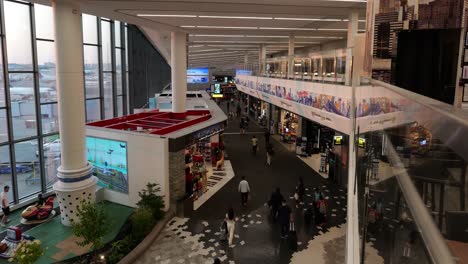 Elevated-view-of-passengers-in-remolded-LGA-terminal-B-with-passengers-walking-to-gates,-entertaining-kids,-and-visiting-stores