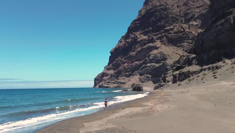 Idyllic-scene-of-a-woman-relaxing-unwinding-at-unspoiled-virgin-beach-in-Gran-Canaria,-Spain-during-summer-time-on-vacations