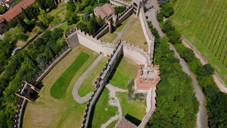 Aerial-overhead-view-showcasing-the-historic-Soave-Castle-in-Italy,-surrounded-by-lush-greenery-and-ancient-walls-on-a-bright-sunny-day