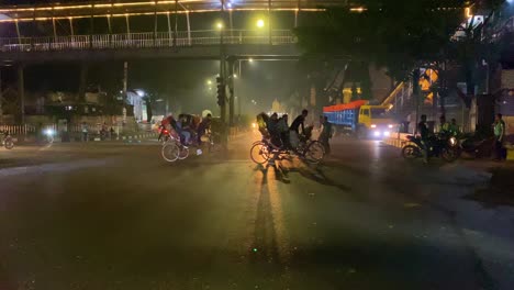 A-bustling-night-scene-in-Dhaka,-Bangladesh,-with-various-modes-of-transportation-including-rickshaws-and-motorbikes-navigating-the-road