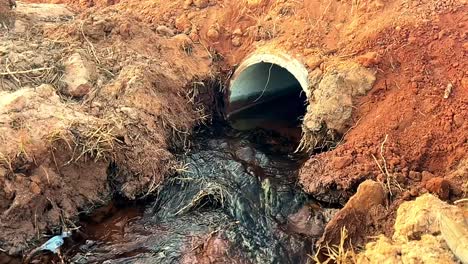 Agua-Clara-Fluyendo-A-Través-De-Una-Tubería-De-Hormigón-Recién-Instalada-En-Un-Puente-De-Arena,-Lo-Que-Ayuda-A-La-Gestión-Y-El-Flujo-Del-Agua.