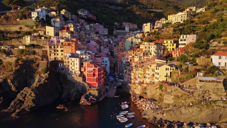 Drone-dolly-in-towards-the-village-of-Riomaggiore-on-the-Ligurian-Coast,-Italy-during-sunset-and-golden-hour