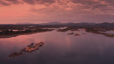 Beautiful-scene-featuring-a-wide-expanse-of-calm-waters-with-scattered-islands-under-the-sky-filled-with-pink-sunset-colors