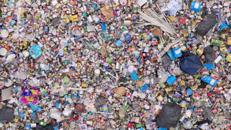 Massive-heap-of-metal-cans-and-tins-on-heap-at-recycling-centre,-aerial-top-down