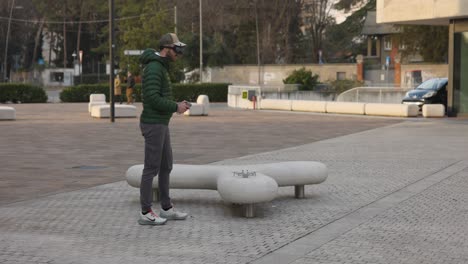 FPV-drone-pilot-in-public-square-takes-off-drone-from-bench-wearing-goggles