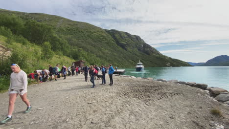 Turistas-Preparándose-Para-Iniciar-Una-Caminata-Por-Las-Montañas-Noruegas-Después-De-Ser-Dejados-Por-Un-Ferry-En-Un-Lago-Verde