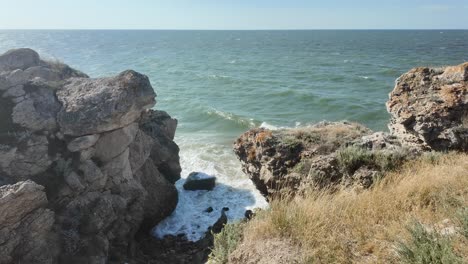 A-breathtaking-view-of-the-rocky-coastline-in-Crimea,-showcasing-waves-crashing-against-the-cliffs-under-a-clear-blue-sky