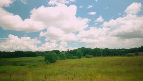 Drive-through-the-Baltic-countryside-reveals-expansive-green-fields-under-a-clear-blue-sky-adorned-with-fluffy-white-clouds