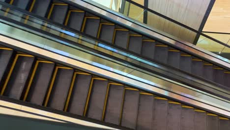 Close-up-two-ways-of-activating-escalators-in-a-mall-without-people—side-view-from-above-of-the-escalators,-Indoor-lighting-with-a-warm-tone