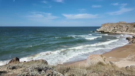 Las-Olas-Rompen-Suavemente-En-La-Playa-De-Arena,-Resaltando-La-Belleza-Natural-De-La-Costa-De-Crimea-Bajo-Un-Cielo-Azul-Claro.