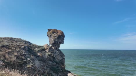 Una-Impresionante-Formación-Rocosa-Que-Se-Asemeja-A-Un-Perfil-Humano-Se-Alza-Majestuosa-Cerca-De-La-Costa-De-Crimea,-Con-El-Mar-De-Azov-Brillando-Al-Fondo.