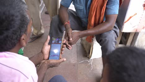 Group-of-daily-wage-workers-watching-live-news-reporting-on-smartphone