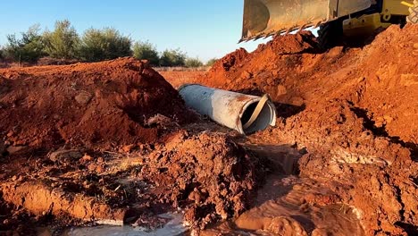 Absenken-Eines-Drainage-Betonrohrs-In-Einen-Ausgehobenen-Sandgraben-Auf-Einer-Brückenbaustelle